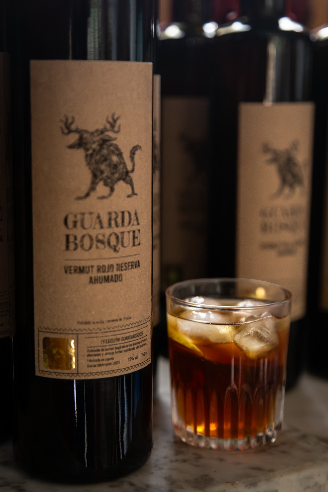 Botella de Guarda Bosque junto a un vaso con hielo
